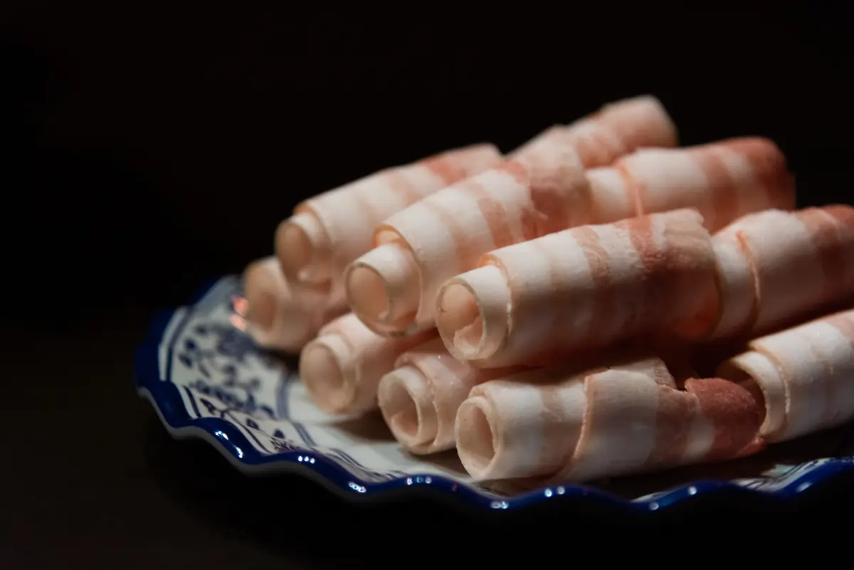 青花瓷盤上捲成卷的帶皮五花白肉