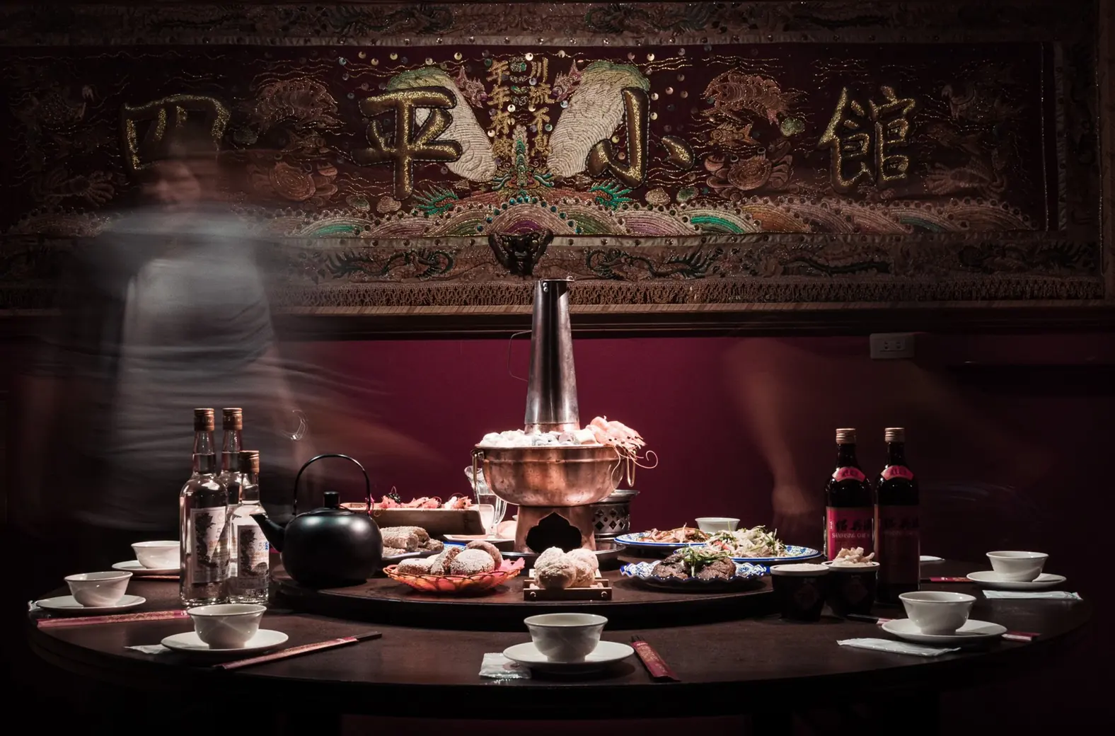 四平小館:繡著店名的大匾額下,一張圓桌圍著炭火銅鍋,人來人往